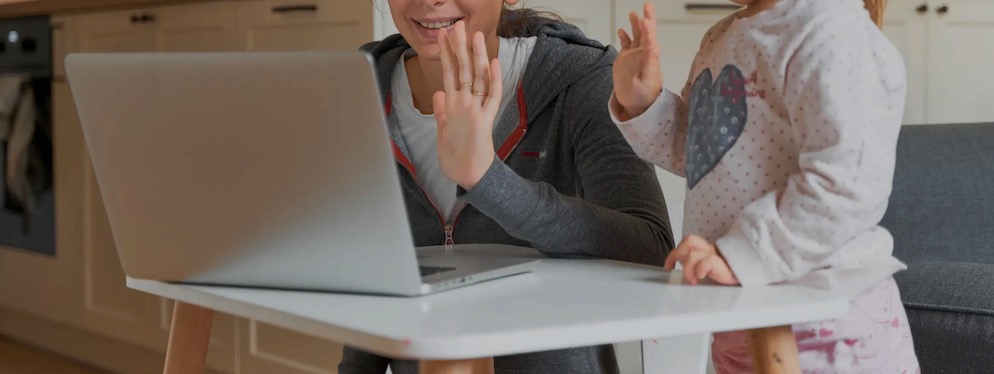 A woman, probably a mother, and a young girl waving to doctor on a laptop at home